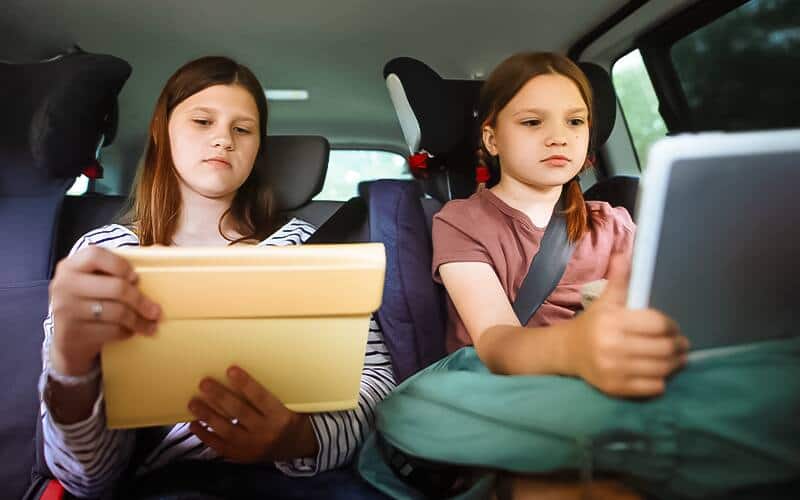 A boy and girl sitting in the car and wearing headphone